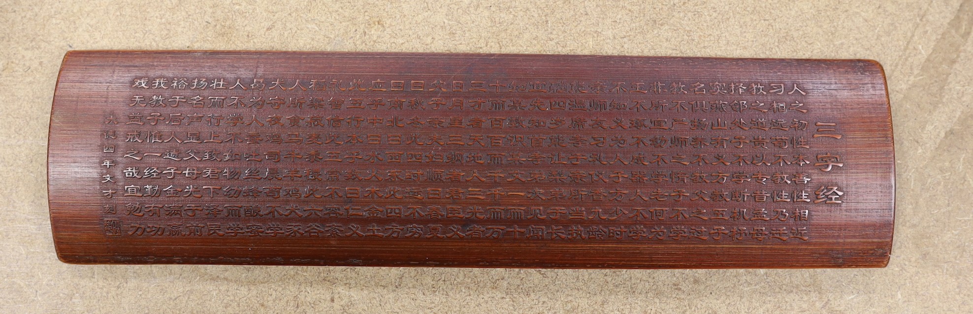 A Chinese bamboo inscribed wrist rest, carved in relief with columns of calligraphy, 30cm wide